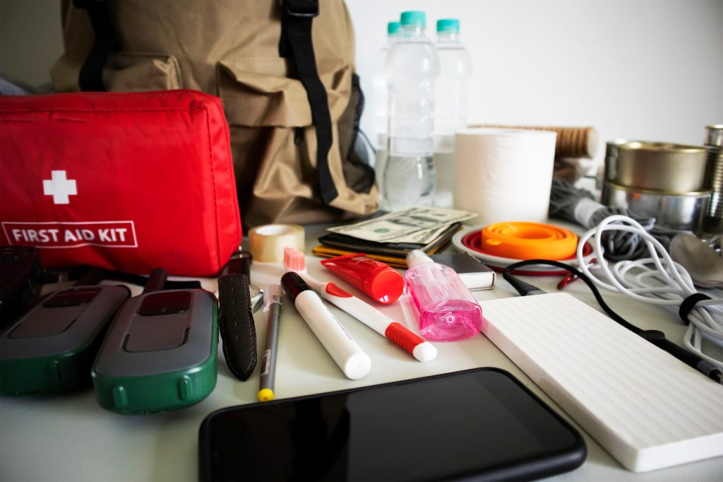 IMPLEMENTING EFFECTIVE ON-HOLD STRATEGIES - Emergency backpack equipment organized on the table. Documents, water, food, first aid kit and another items needed to survive. phone for communications and emergency contact - on hold marketing concept