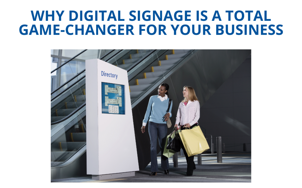 smiling women with shopping bags in retail mall checking out digital sign with mall directory displayed explaining what is on both floors next to escalator