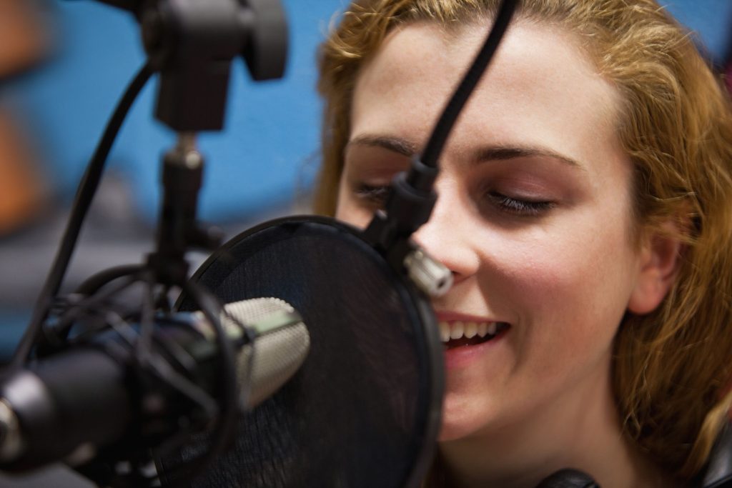 woman in recording studio speaking into microphone for professional voice recording 