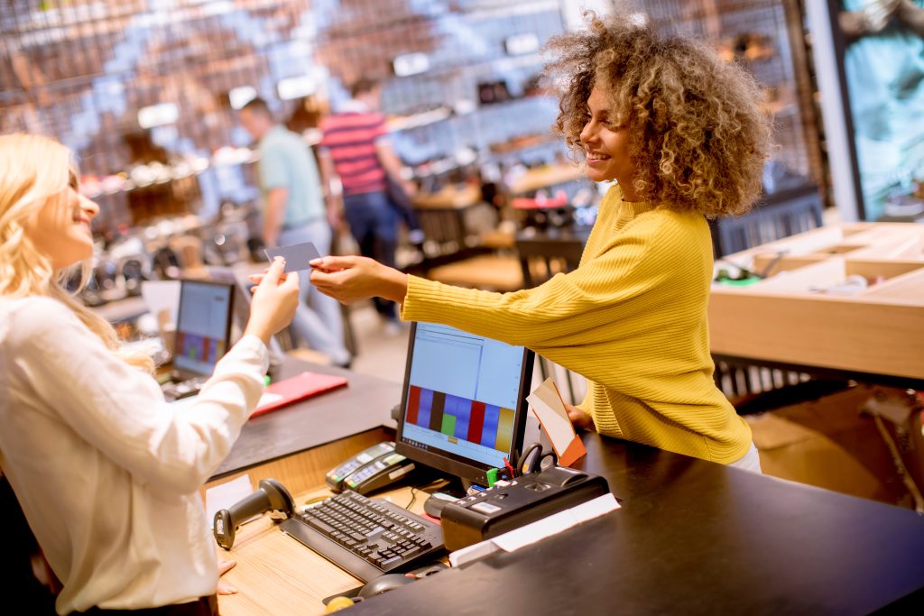 Retail shopping environment where woman is making a purchase. Smiling cashier is taking card from smiling customer 