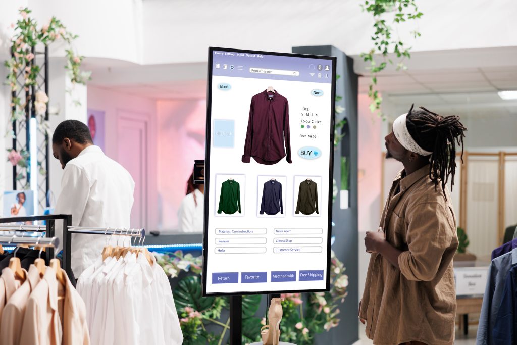 man looks at digital sign showing available clothing in a department store