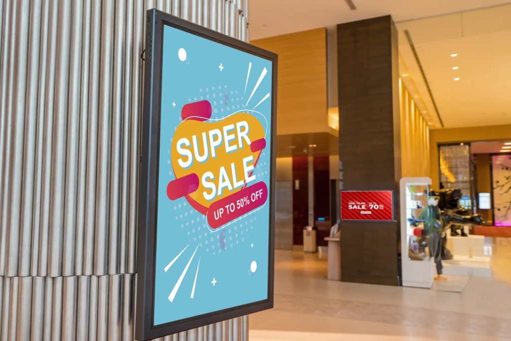 integrated marketing concept showing digital signage in a place that utilizes audio marketing as well - digital signs on walls of a mall or department store -  signs show sales going on now