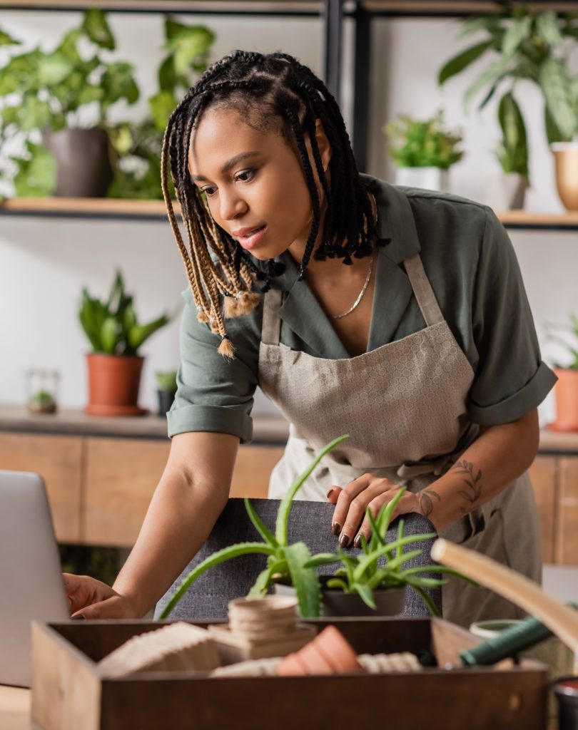 Understanding the Importance of New Year’s Goals for Businesses - Employee wearing apron looks at computer on desk