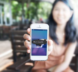 Woman holding smartphone showing Music Zeppelin app screen