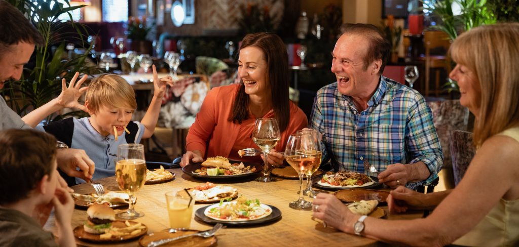 In the competitive restaurant industry, creating the perfect dining ambiance with the right mix of overhead music and strategic messaging can significantly enhance the overall customer experience - Family dining at a restaurant, laughing at a child who is playing with their food and pretending to be a walrus